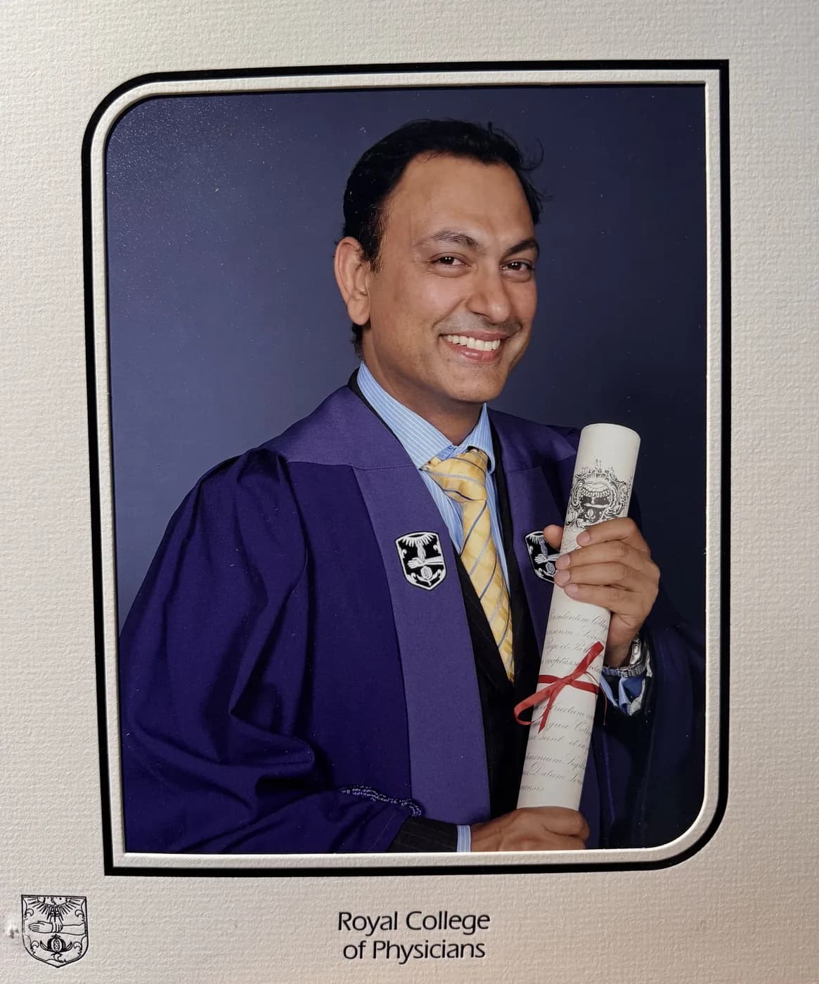 Dr Dhiraj Gupta in the purple and gold gown of the Royal College of Physicians, holding his fellowship scroll, London 2012.